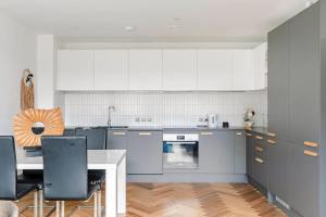 Una cocina con gabinetes blancos y una mesa con sillas. en A Modern Lavish En-suite Bedroom, en Londres 21 fotos más