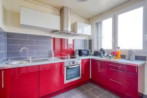 a kitchen with red cabinets and a person in the kitchen at Saphir T2 proche Paris in Vitry-sur-Seine +15 photos