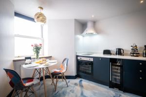 鮑內斯溫德米爾的住宿－Brand New Apartment Central Location Hot Tub，厨房配有蓝色橱柜和桌椅