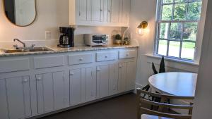 a kitchen with white cabinets and a table and a sink at Whimsical Cottage w/ Pond View in Dundee