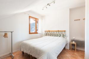 een witte slaapkamer met een bed en een raam bij Chalet Clos Gauthier in La Salle Les Alpes
