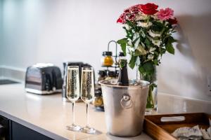 a counter with two wine glasses and a vase with flowers at Brand New Apartment Central Location Hot Tub in Bowness-on-Windermere +29 photos