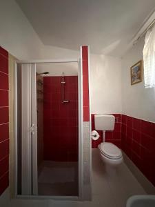 a bathroom with a toilet and a shower with red tiles at Casa Himera Fontane Bianche in Fontane Bianche