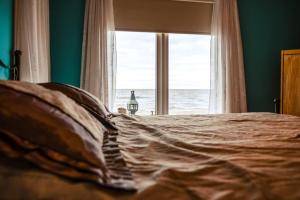 a bed with a view of the ocean from a window at Les pieds dans le sable in Chambord