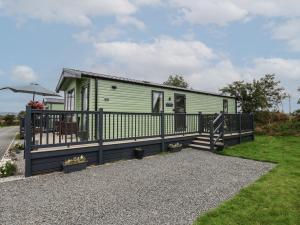 a green holiday home with a black fence at Jean's Place in Ganton