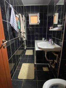 La salle de bains est pourvue de carrelage noir, d'un lavabo et de toilettes. dans l'établissement Apartment for rent, à Galaţi