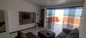 a living room with a couch and a tv at Cobertura Pé na Areia 15 m Mar in Olivença
