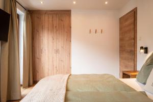 a bedroom with a bed and a wooden cabinet at Apartments Fliegerbichl - Familie Voithofer in Bramberg am Wildkogel