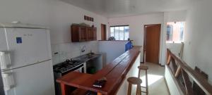 a kitchen with a wooden table and a counter top at Cobertura Pé na Areia 15 m Mar in Olivença