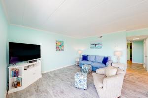 大洋城的住宿－Assateague House 306，客厅配有蓝色的沙发和电视