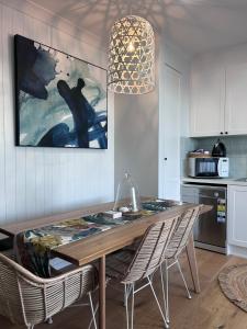 Catherine Hill Bay的住宿－Bluemoon Getaway，餐桌、椅子和墙上的绘画