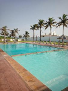 a large swimming pool with chairs and palm trees at Hermosa Residencia junto al mar in Veracruz