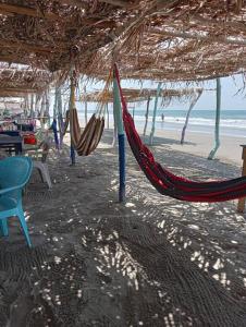 a beach with a hammock and chairs and the ocean at Hermosa Residencia junto al mar in Veracruz