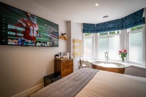 1 dormitorio con cama, bañera y TV en Glen Wynne Recently Renovated - FREE off-site Health Club access with Pool, Sauna, Steam Room & Gym Short 5 Minute Drive Away, en Windermere 14 fotos más