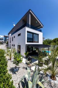 a white house with a black roof at Luxury Villa Adria Apartments in Krk