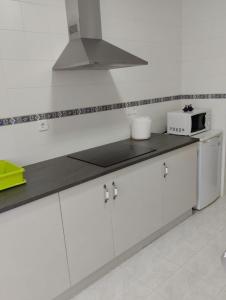 uma cozinha com armários brancos e um forno com placa de fogão em ALVAFER em Ribadeo