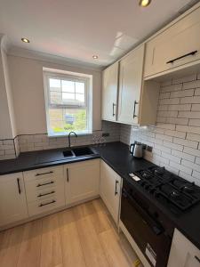 cocina con armarios blancos y encimera negra en Stylish Penarth Marina Apartment, en Cardiff