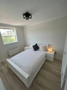 a white bedroom with a large bed and a window at Stylish Penarth Marina Apartment in Cardiff