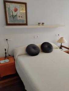 uma cama branca com duas almofadas pretas em ALVAFER em Ribadeo