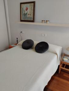 uma cama branca com duas almofadas pretas em ALVAFER em Ribadeo