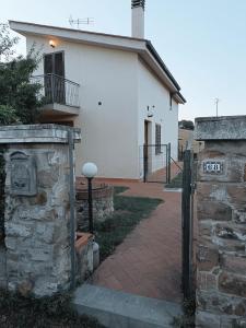 uma casa branca com um portão e um passeio de tijolos em A Casa di Emilie em Castelfiorentino