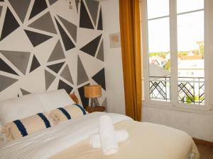 1 dormitorio con cama blanca y pared geométrica en Cosy Home_A 30 minutes de Disneyland en Joinville-le-Pont