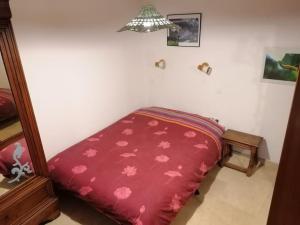 La maison de la vigne في بودوان: غرفة نوم بها سرير احمر وعليه ورد وردي