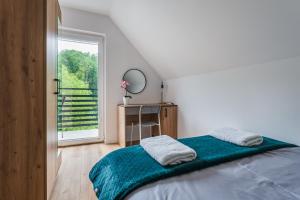 a bedroom with a bed and a desk and a window at Domek RogatY in Szczawnica