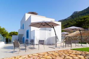 eine Terrasse mit Stühlen und Sonnenschirmen vor einem Gebäude in der Unterkunft Tenuta Pezzeselle - Casa Vacanze in Marettimo