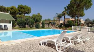 a pair of white chairs sitting next to a swimming pool at Masseria San Nicola B&B in Torre Santa Susanna