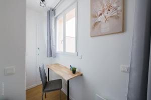 Cosy Appart Proche Paris في مونتروي: طاولة وكرسي في غرفة مع نافذة