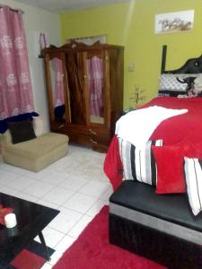 a bedroom with a red and white bed and a chair at Silver Lining in Spanish Town