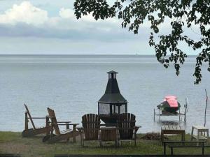 un grupo de sillas y una mesa y un barco en el agua en Maison sur la plage, en Chambord