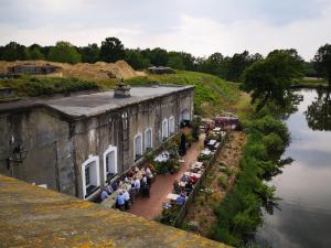 een groep mensen die buiten een gebouw naast een rivier zitten bij Erfgoedlogies Fort Liezele 