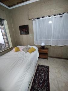 um quarto com uma grande cama branca e uma janela em CASA ANGELITA en SAAVEDRA em Buenos Aires