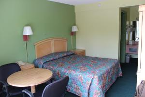 Habitación de hotel con cama, mesa y sillas en Travelers Inn Gainesville, en Gainesville