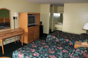 a hotel room with two beds and a desk and a television at Travelers Inn Gainesville in Gainesville