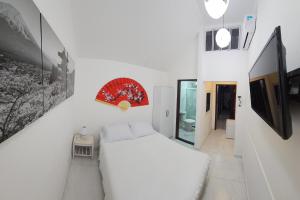 a white bedroom with a white bed and a mirror at Pousada Tu Y Mar in Arraial do Cabo