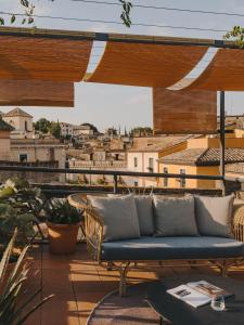 a couch on a balcony with a view of a city at Hotel Palau Fugit in Girona