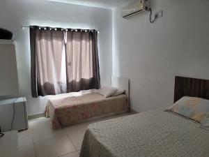 1 dormitorio con 2 camas y ventana en Vó Paulina suites, en Penha