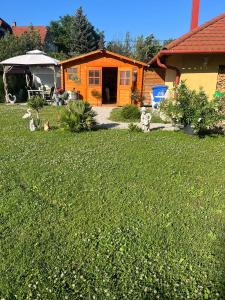 een oranje huis in een tuin met een grasveld bij Rege apartman 3 in Alsóörs