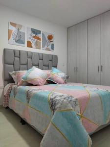um quarto com uma cama grande com lençóis e almofadas coloridos em Apartamento nuevo, próximo al metro y CC Mayorca em Sabaneta