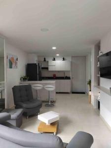 uma sala de estar com um sofá e cadeiras e uma cozinha em Apartamento nuevo, próximo al metro y CC Mayorca em Sabaneta