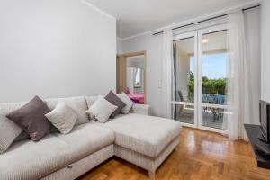 a white living room with a couch and a balcony at Apartments Bugenvila Brzac in Brzac
