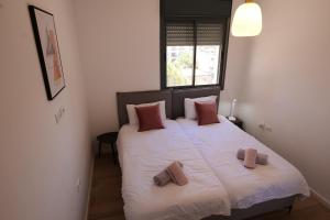 Beautiful 2BR near Mahane Yehuda في القدس: غرفة نوم بسرير ابيض كبير مع وسادتين