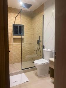 a bathroom with a shower with a toilet and a sink at Knightsbridge Hotel & Suites in Abuja