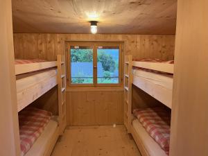 eine Blockhütte mit 2 Etagenbetten und einem Fenster in der Unterkunft Sunnehuesli in Braunwald