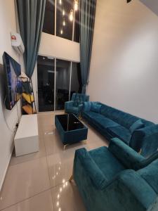 a living room with blue couches and a tv at Metropol Serviced Apartment in Bukit Mertajam