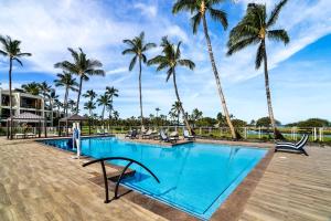 a swimming pool with palm trees in the background at Mauna Lani Terrace J101 in Waikoloa