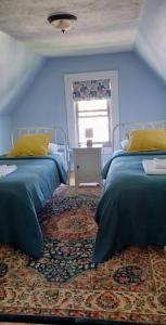 a blue bedroom with two beds and a window at Guest suite in historical district in Gloucester